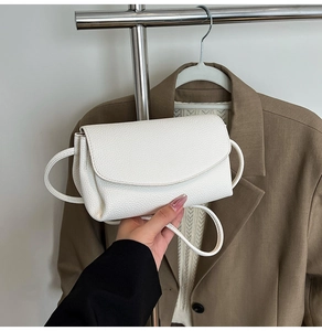 Vue détaillée de la texture du cuir grainé blanc et du rabat d'un petit sac carré chic