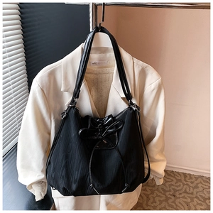 Detail view of the black wavy texture fabric and leather drawstring bow on the tote bag