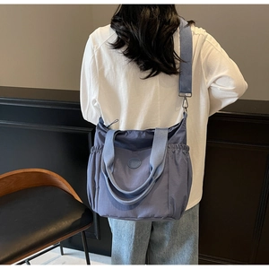 Blue nylon tote bag showing large capacity and drawstring side pockets on model
