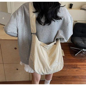 Vista posteriore di una modella con la borsa tote in tela beige e tracolla regolabile