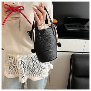 Detail of black textured bucket bag with white drawstring canvas inner pouch and handle