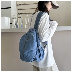 Détail du sac à dos en jean bleu avec poche latérale pour bouteille et bretelles réglables