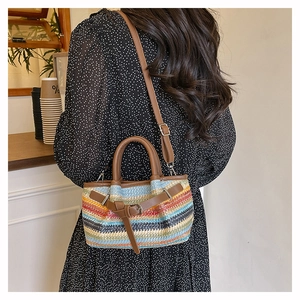Detail of colorful striped woven crossbody bag with leather handles in a cafe setting