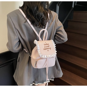 Close-up of pink leather backpack with Today I did Nothing embroidery and ruffled trim