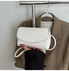 Gros plan d'un sac bandoulière en cuir blanc à motif lychee avec une fine lanière
