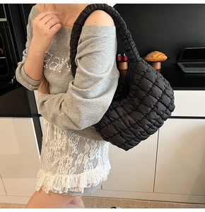Close-up of black quilted cloud bag with padded texture and stylish wide strap