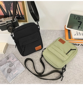 Detail of waterproof canvas crossbody phone bags in black and green with leather logo