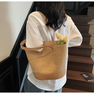 Détail d'un sac cabas en paille tissée à dentelle ajourée porté par un mannequin en vacances