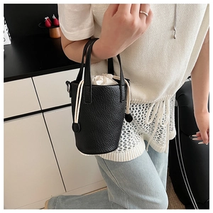 Detail of black lychee grain leather bucket bag with cream drawstring inner pouch