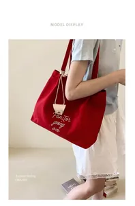 Detail of red canvas tote bag featuring white cursive embroidery and small leather card pouch