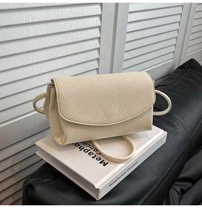 Détail du sac bandoulière blanc crème avec texture grainée sur un livre déco