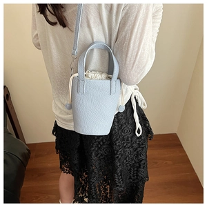 Close-up of light blue litchi grain leather bucket bag with cream drawstring closure detail