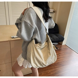 Dettaglio della borsa tote grande in tela beige con tasca laterale e logo ricamato