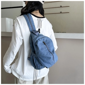 Vue détaillée d'un sac bandoulière en jean bleu durable porté par un mannequin en extérieur