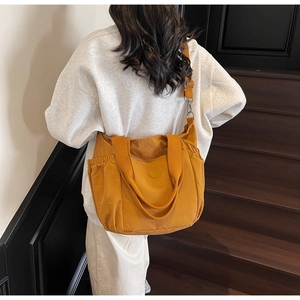 Detail of yellow canvas tote bag showing adjustable straps and front pocket for daily use