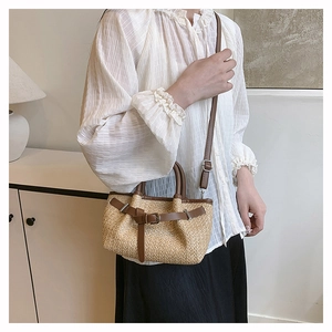 Detail of hand-woven straw tote bag with brown leather straps and adjustable shoulder belt