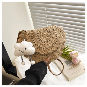Detail of hand-woven straw saddle bag with wavy edges and cloud plush charm