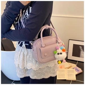 Detailed side view of light purple patent leather pillow bag with cute plush monster charm