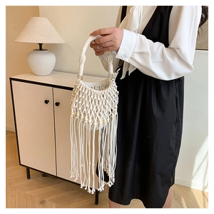 Detailed macro view of white macrame hand-woven bag with wooden beads and long tassels