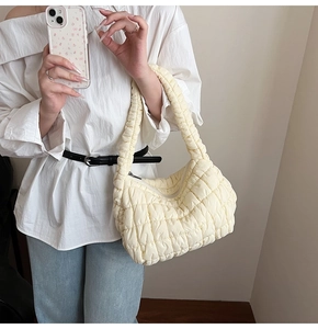 Detalle de textura acolchada y correa ancha en el bolso hobo color blanco crema