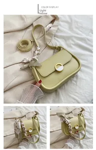 Vue détaillée d'un sac selle jaune clair avec boucle dorée et décor en foulard de soie