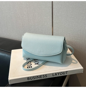 Détail du petit sac carré en cuir bleu clair à motif litchi sur des livres décoratifs