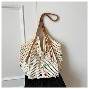 Close-up of beige crochet tote bag with colorful sequins and brown shoulder straps