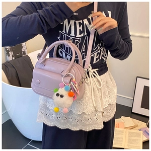 Detail of lavender PU leather pillow bag featuring a cute white monster plush pendant