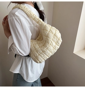 Detail view of beige quilted cloud bag with ruched nylon strap on model's shoulder