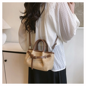 Detail of woven straw beach bag with brown leather straps and metal buckle decoration