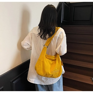 Vista posteriore di una borsa a tracolla in tela gialla su una modella in interni