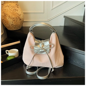 Detail of pink satin tote bag with metallic silver bow decoration and long strap