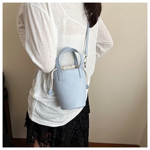 Detail view of a light blue bucket bag featuring lychee grain texture and drawstring inner
