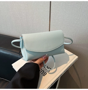 Détail du sac bandoulière bleu clair avec texture litchi et rabat semi-circulaire
