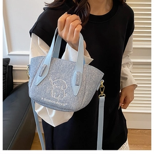 Detail of light blue denim tote with cute puppy embroidery and golden hardware