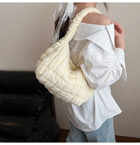 Close-up of beige quilted cloud bag texture and soft padded single shoulder strap