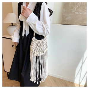 Detail of white bohemian crochet bag with wooden beads and long fringe tassels