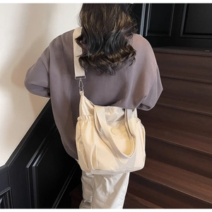 Detail of cream canvas tote bag showing adjustable wide strap and side elastic pocket