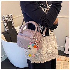 Detail of light purple leather handbag with white sheep plush charm and metal strap