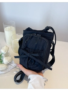 Minimalist black nylon crossbody bag with bow detail and adjustable shoulder strap