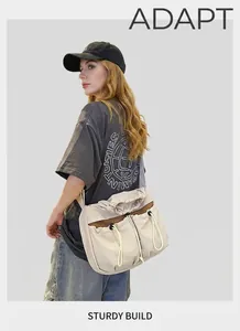 Detail of beige cargo crossbody bag featuring drawstring pockets and wide black strap
