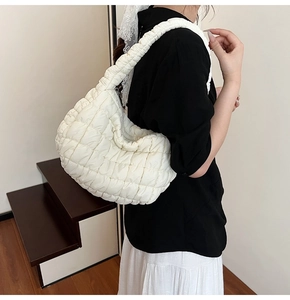 Detail view of white quilted cloud bag with ruched shoulder strap and puffy texture