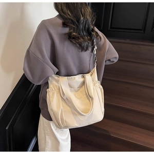 Detailed back view of a beige nylon tote bag with side pockets on a staircase