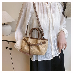 Close-up detail of a mini woven straw tote bag with brown leather handles and strap