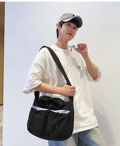 Detailed view of black functional nylon crossbody bag with drawstring pockets on model