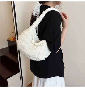 Side view of white quilted hobo bag featuring soft pleats and a textured shoulder strap