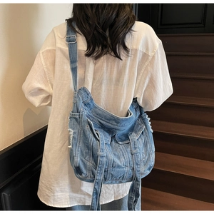 Detail of vintage blue denim crossbody bag featuring utility pockets and distressed edges