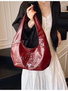 Burgundy punk underarm bag with silver star rivets shown held by a model