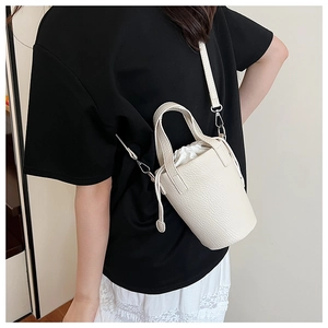 Detailed view of cream leather bucket bag with textured grain and drawstring inner pouch