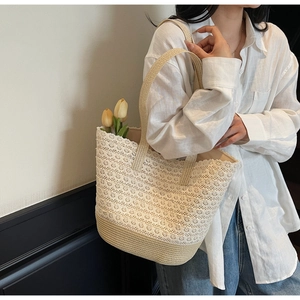 Détail d'un sac cabas en paille tressée avec dentelle blanche délicate et bandoulières